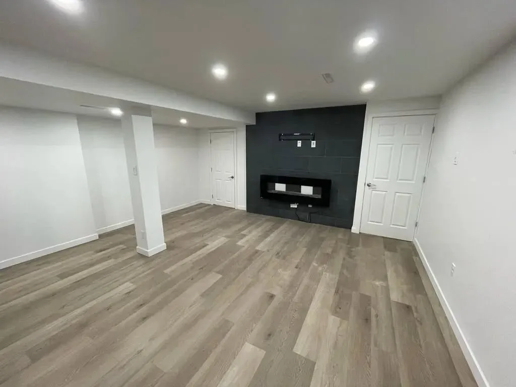 Sous-sol terminé à Laval, plancher imitation bois et mur de foyer en tuile foncée
