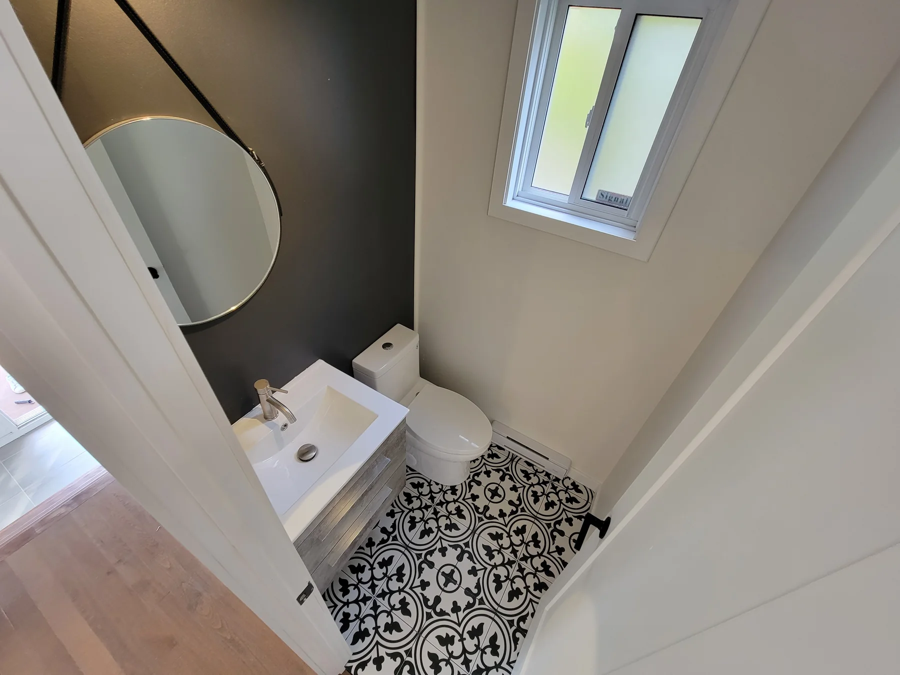 Powder room with patterned floor tile and a charcoal accent wall