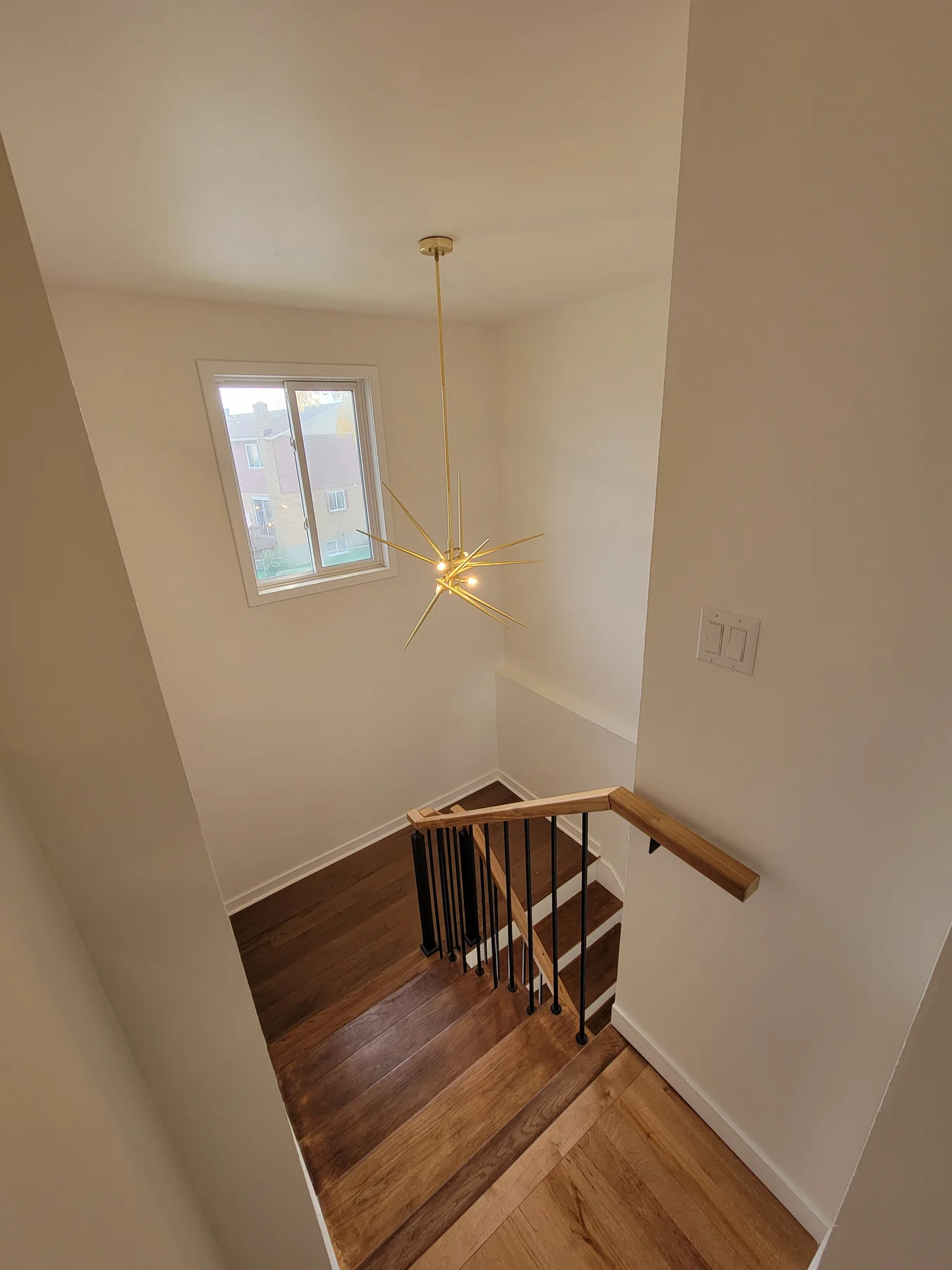 Stairwell with a starburst pendant and oak handrail