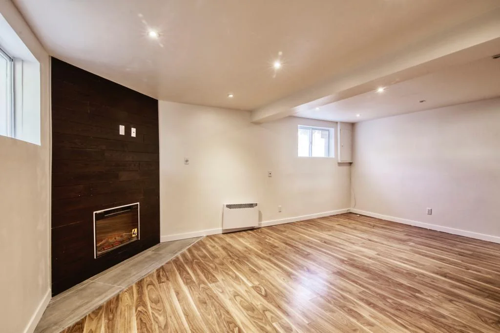 Basement family room with a wood-accent fireplace wall