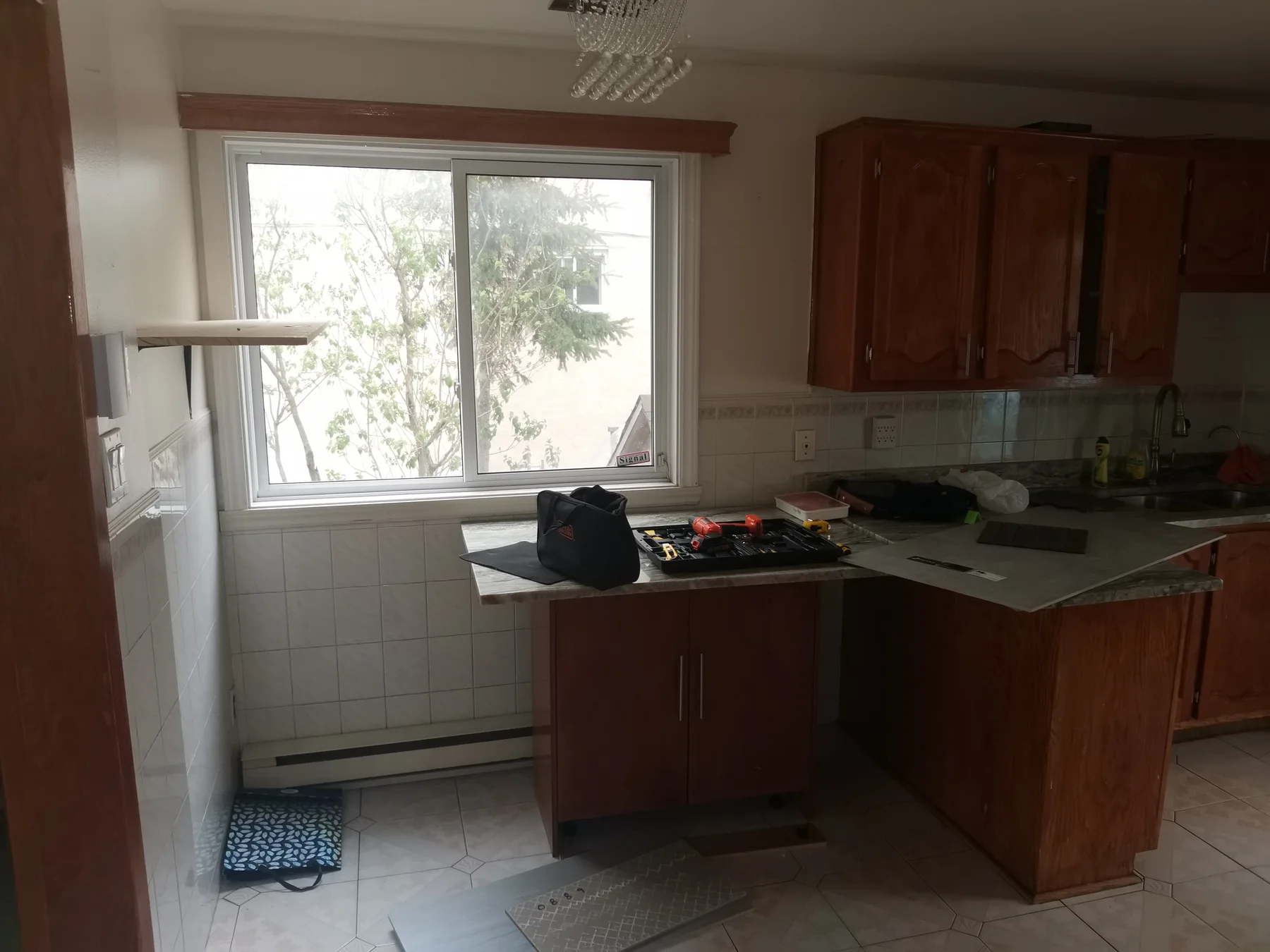 Kitchen before: honey-oak cabinets and white tile, the day work began