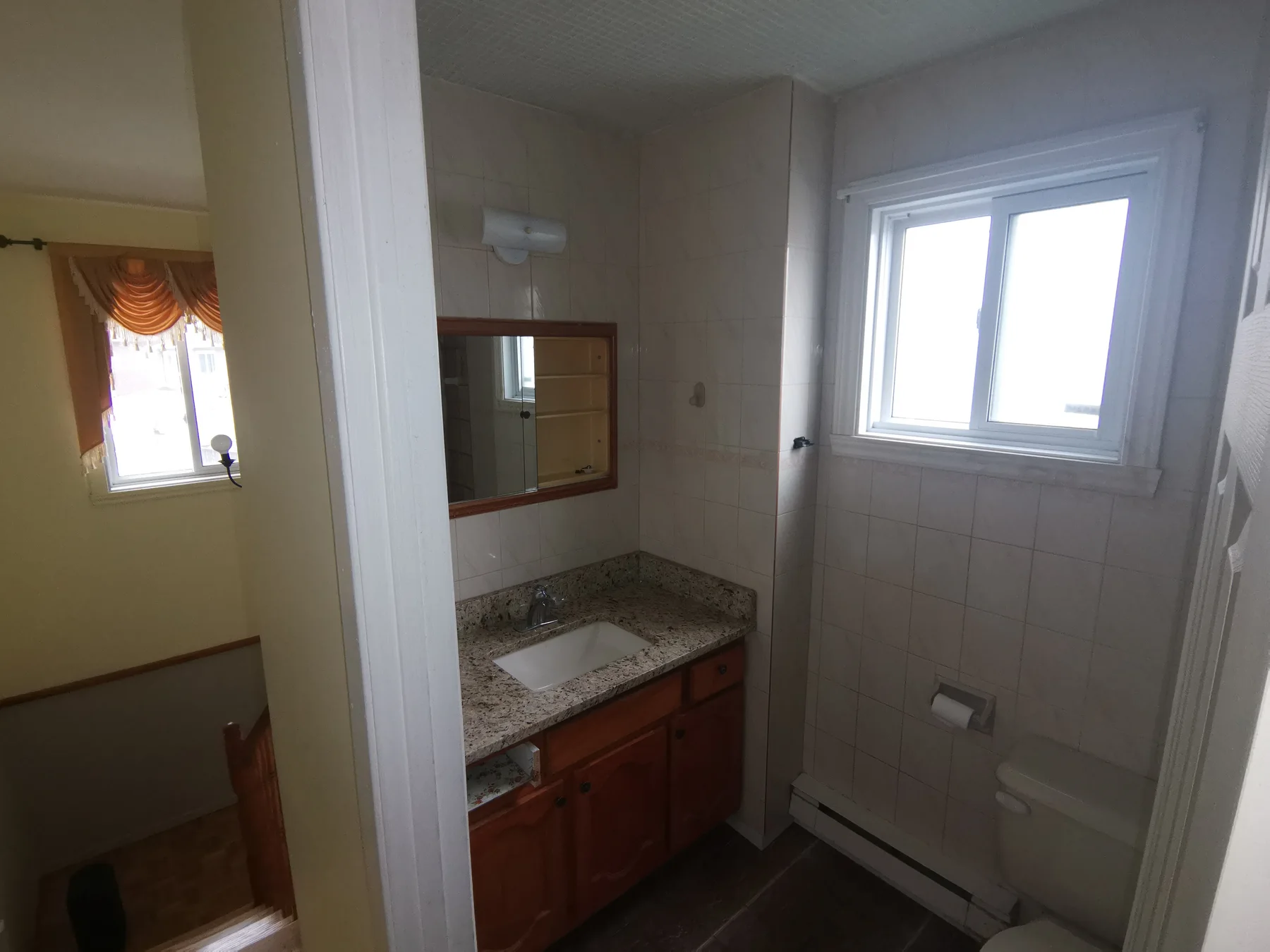 Main bathroom before: dated oak vanity and beige tile everywhere