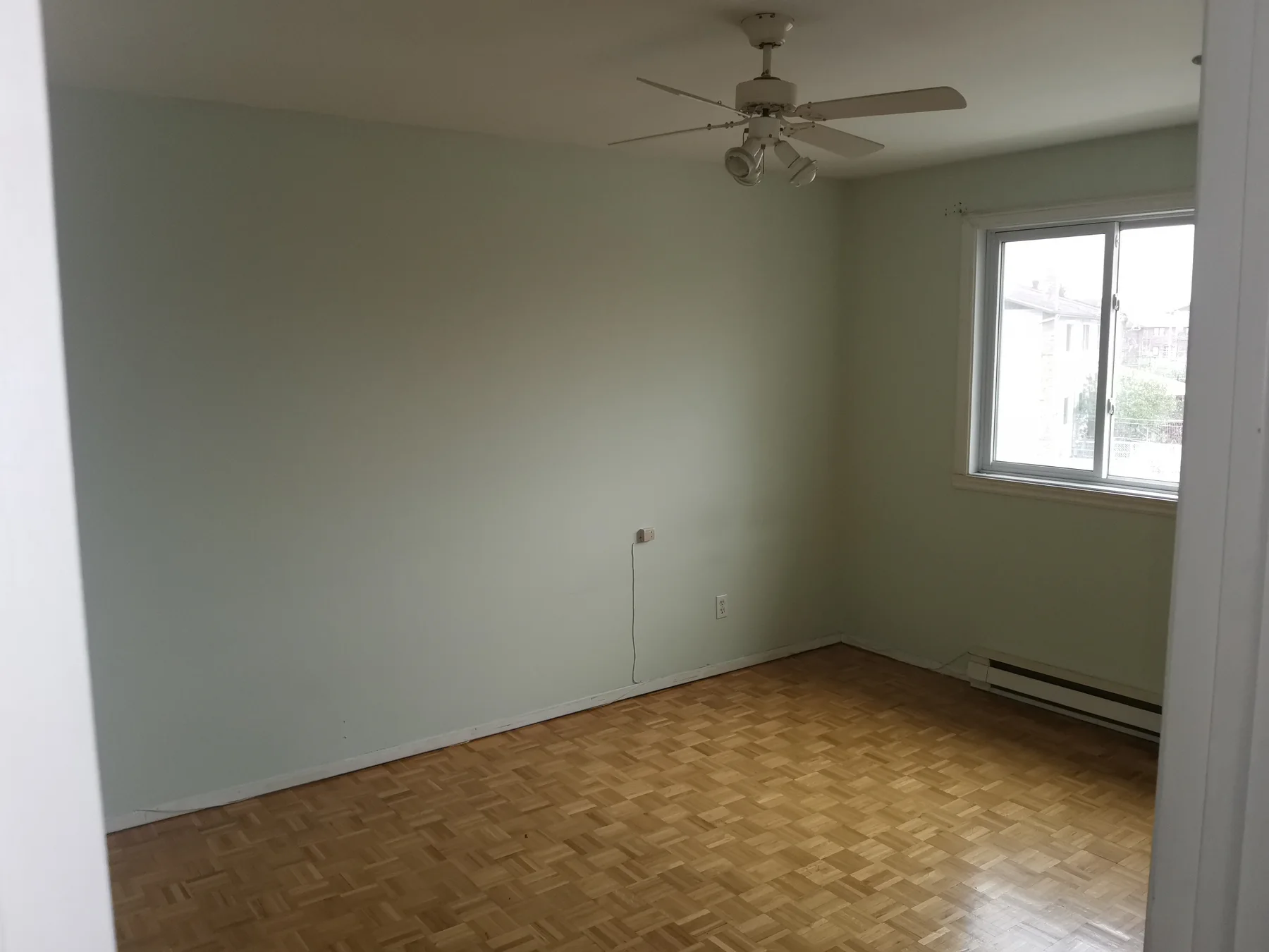 Bedroom before: pale-green walls, parquet floor and an aging ceiling fan
