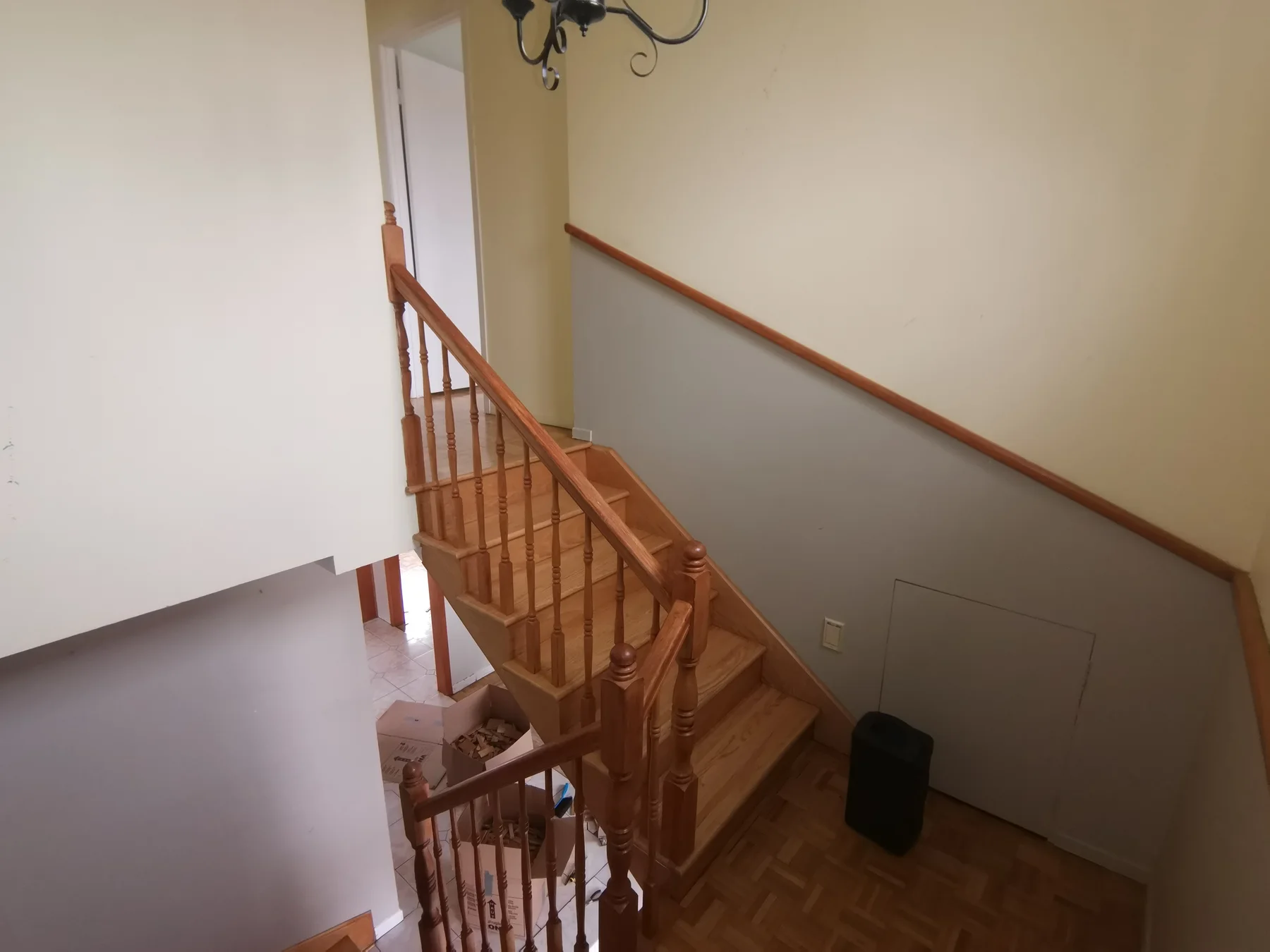 Stairwell before: honey-oak railings and a two-tone paint scheme