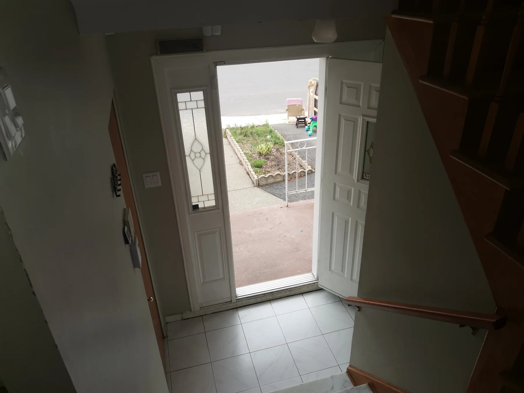 Front entry before: dated tile floor and the porch beyond the open door